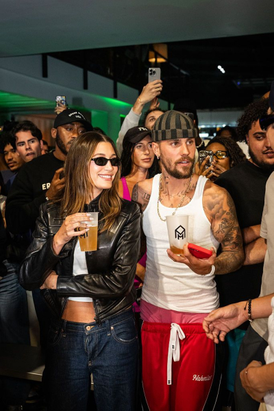 Hailey and Justin Bieber pose at an event. Hailey wears jeans and a leather jacket with a simple sheer white manicure.