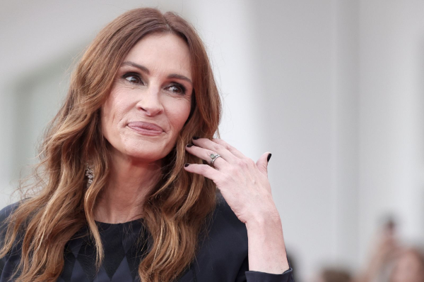 Julia Roberts poses on the red carpet in a navy gown. She has short dark nails.